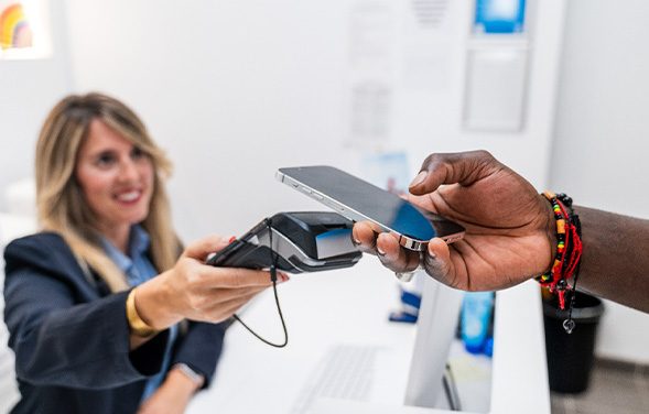 Patient using phone to pay for care in dental office