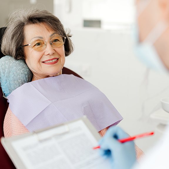 Dentist making notes on clipboard while talking to patient