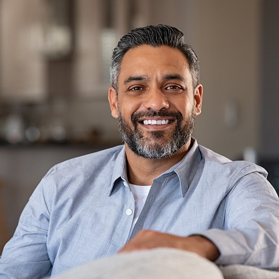 Man in blue shirt smiling on couch