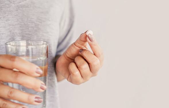 a person holding a pain reliever and glass of water